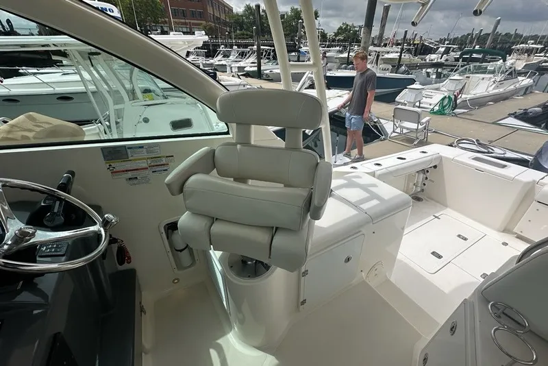 Slide: The Image of 2013 Pursuit OS 345 Offshore boat interior at marina, featuring helm and seating area. - 14