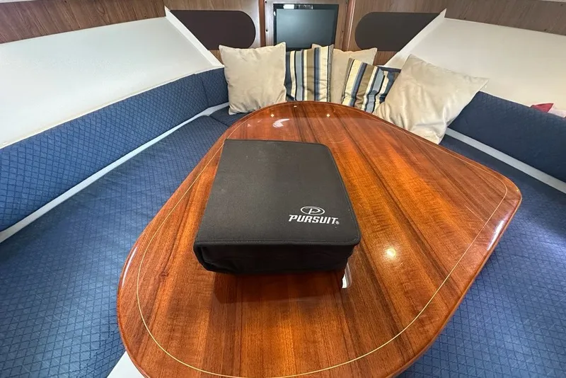 Slide: The Image of Interior of 2013 Pursuit OS 345 Offshore boat with wooden table and cushioned seating. - 22