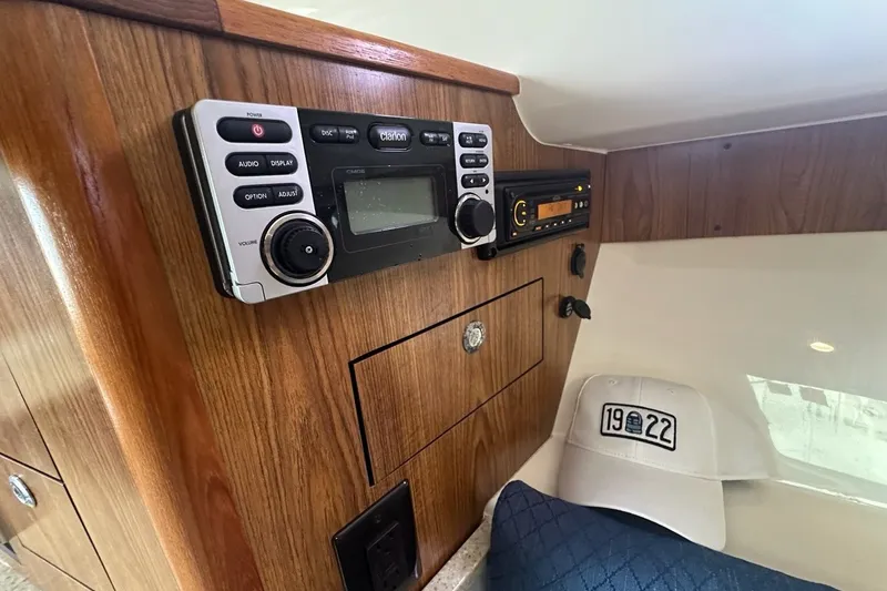 Slide: The Image of 2013 Pursuit OS 345 Offshore cabin with audio system and cap on wooden panel. - 20