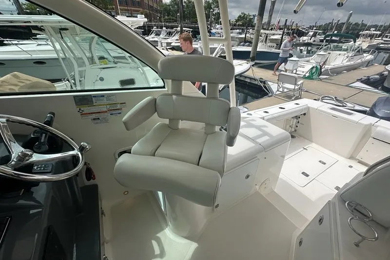 Slide: The Image of 2013 Pursuit OS 345 Offshore boat interior with helm seat and steering wheel. - 13
