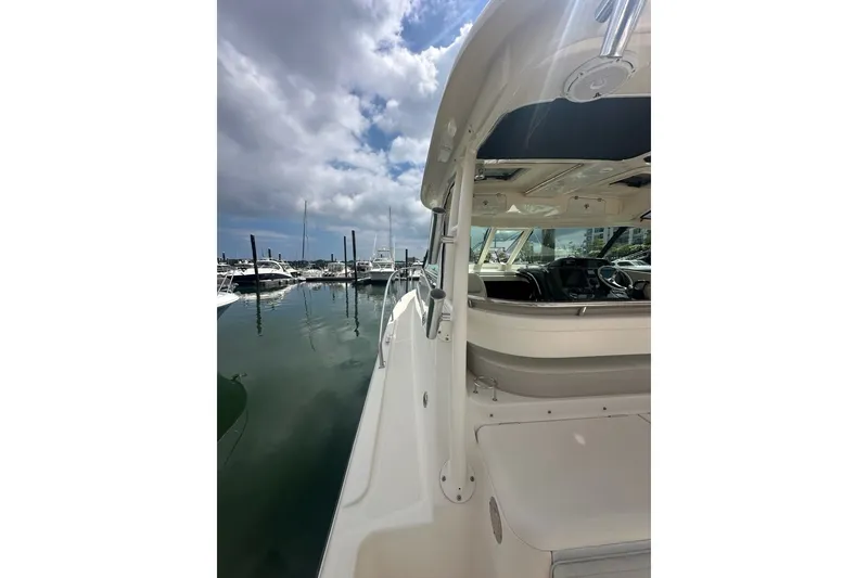 Slide: The Image of 2013 Pursuit OS 345 Offshore boat docked at marina under cloudy sky. - 31