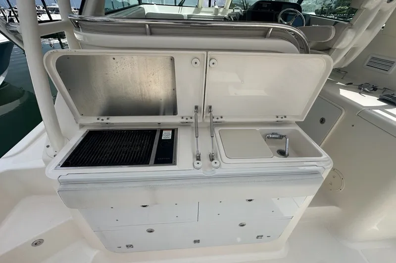Slide: The Image of 2013 Pursuit OS 345 Offshore boat galley with grill and sink setup. - 28