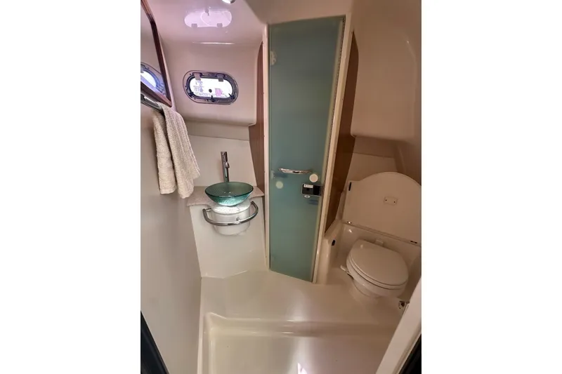 Slide: The Image of 2013 Pursuit OS 345 Offshore boat bathroom with modern sink, toilet, and towel rack. - 24