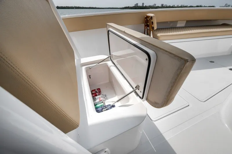 Slide: The Image of Open cooler on 2020 Bahama 41 boat with drinks inside, beige seating, and ocean view. - 24