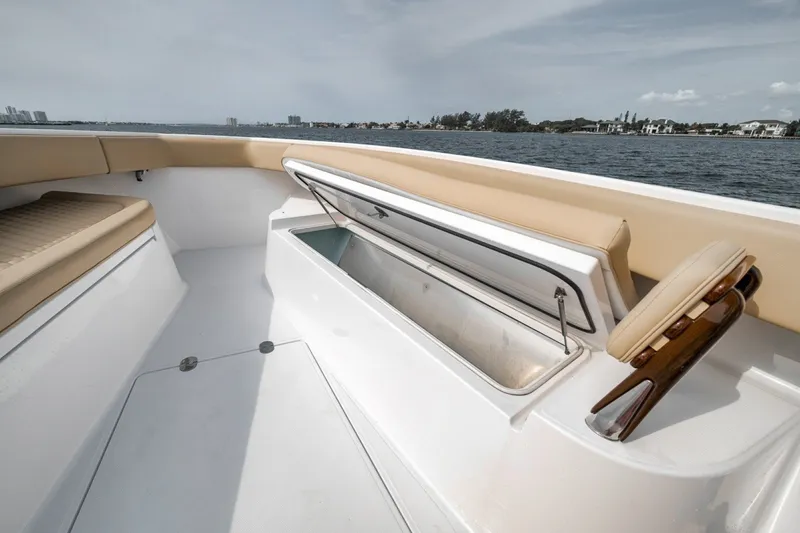 Slide: The Image of 2020 Bahama 41 boat interior with open storage compartment, beige seating, and ocean view. - 20