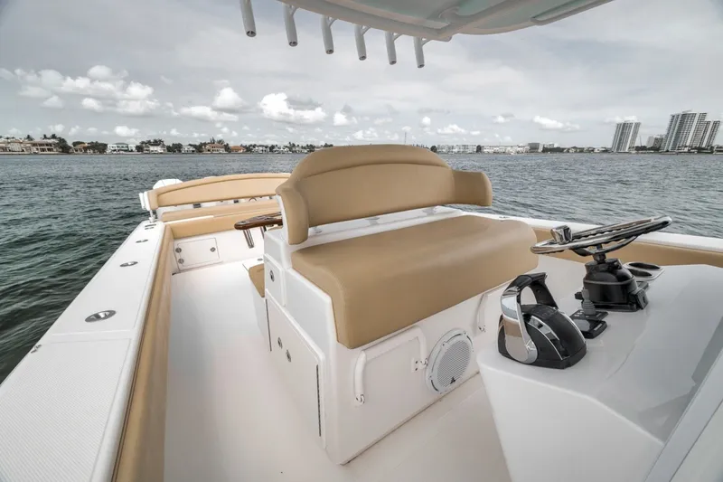 Slide: The Image of 2020 Bahama 41 boat interior with tan seating and steering wheel, overlooking waterfront skyline. - 27
