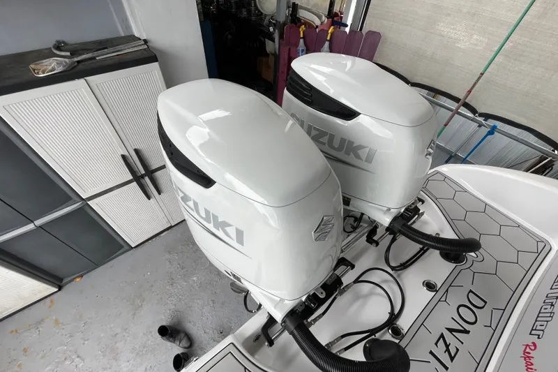 Slide: The Image of Twin Suzuki outboard engines on a 1998 Donzi 29 ZF Cuddy boat in a garage. - 52