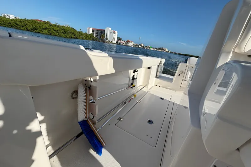 Slide: The Image of 2014 Robalo R300 Center Console boat interior with cleaning tools, docked by scenic waterfront. - 19