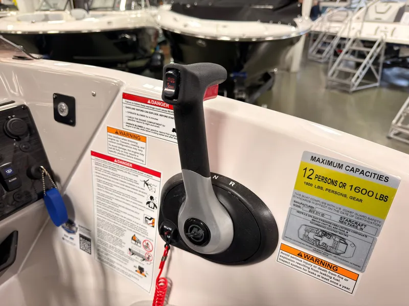 Slide: The Image of Close-up of a throttle lever on a Starcraft 211SVXIO boat, surrounded by warning labels and capacity signs. - 27