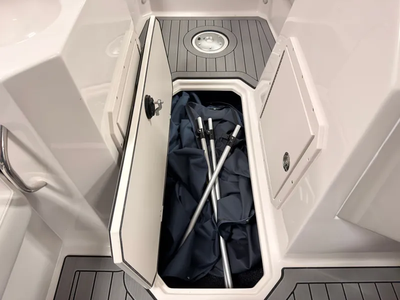 Slide: The Image of An open storage compartment on a boat reveals two metal poles and a tarp on gray flooring. - 34