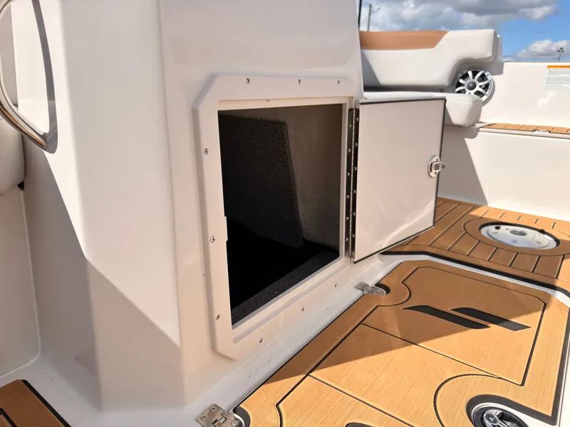 Slide: The Image of The image shows the interior of a Starcraft 211SVXIO boat with storage space and wooden flooring. - 49