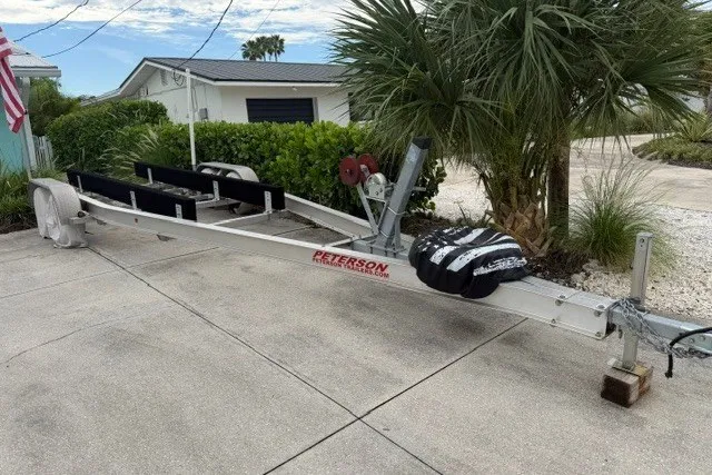 Slide: The Image of Boat trailer for 2019 Carolina Skiff 24 DLX parked on driveway near palm trees. - 18