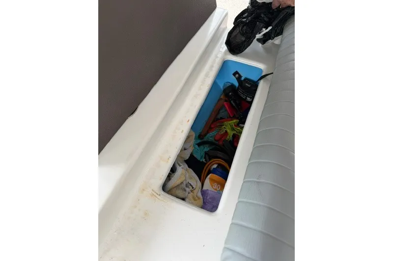 Slide: The Image of Storage compartment in a 2019 Carolina Skiff 24 DLX boat, containing various tools and items. - 14