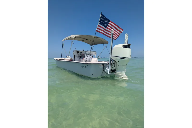 The Image of 2019 Carolina Skiff 24 DLX boat with American flag on calm water. - 0