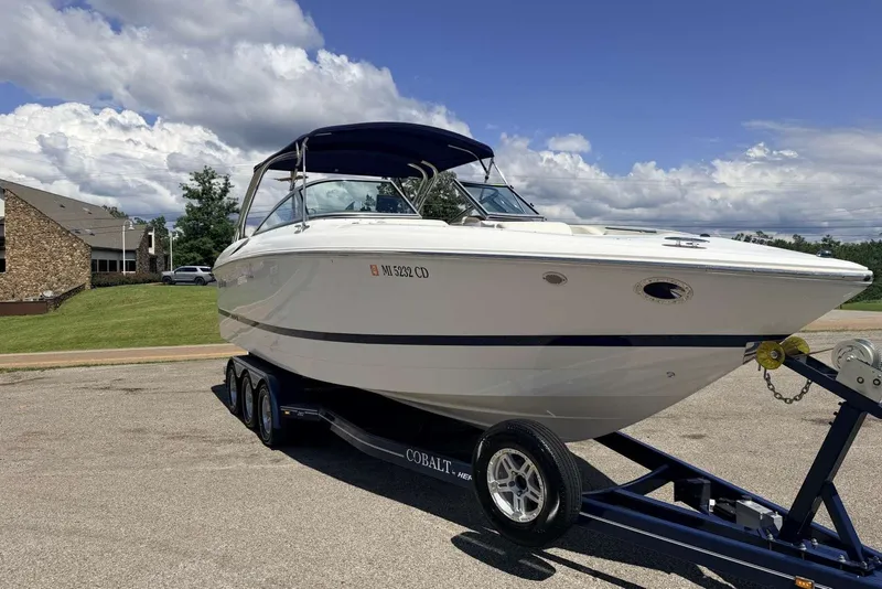 Slide: The Image of 2008 Cobalt 282 boat on trailer, parked outdoors under a cloudy sky. - 2