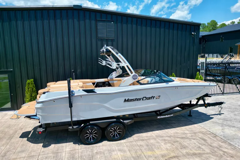 Slide: The Image of 2026 MasterCraft XT24 boat on trailer, parked outdoors, with sleek design and modern features. - 24