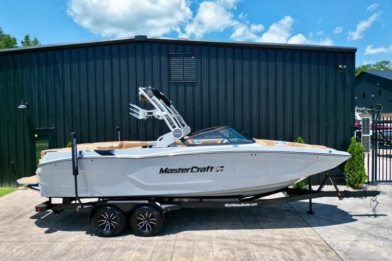Slide: The Image of 2026 MasterCraft XT24 boat on trailer, parked outside a black building. - 17