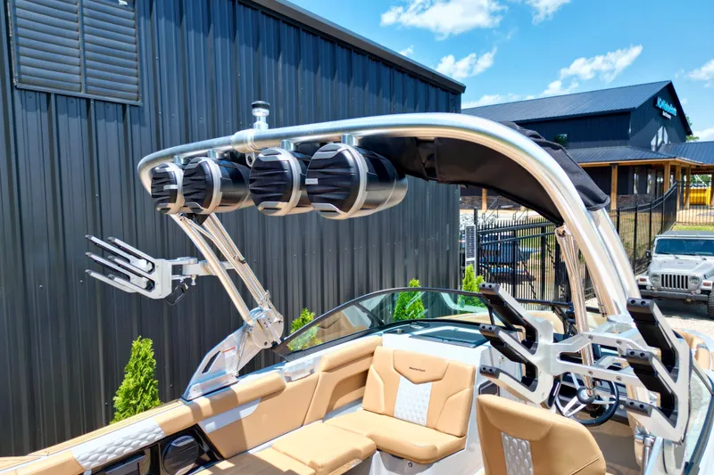 Slide: The Image of 2026 MasterCraft XT24 boat with tower speakers and wakeboard racks, parked outdoors. - 11