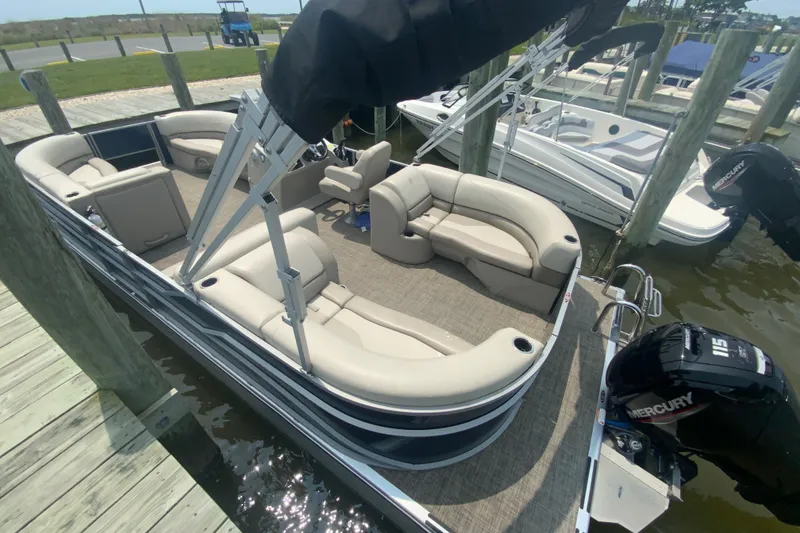 Slide: The Image of 2023 Cypress Cay Seabreeze 232 pontoon boat docked, featuring spacious seating and Mercury outboard motor. - 2