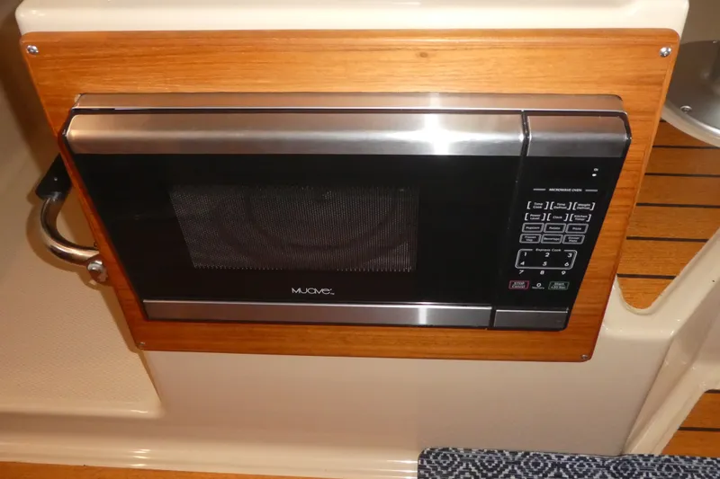 Slide: The Image of Built-in microwave in 2019 Ranger Tugs R-27 boat interior, featuring wood paneling. - 34