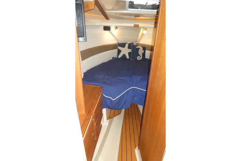 Slide: The Image of 2019 Ranger Tugs R-27 cabin interior with blue bedding and nautical-themed pillows. - 38