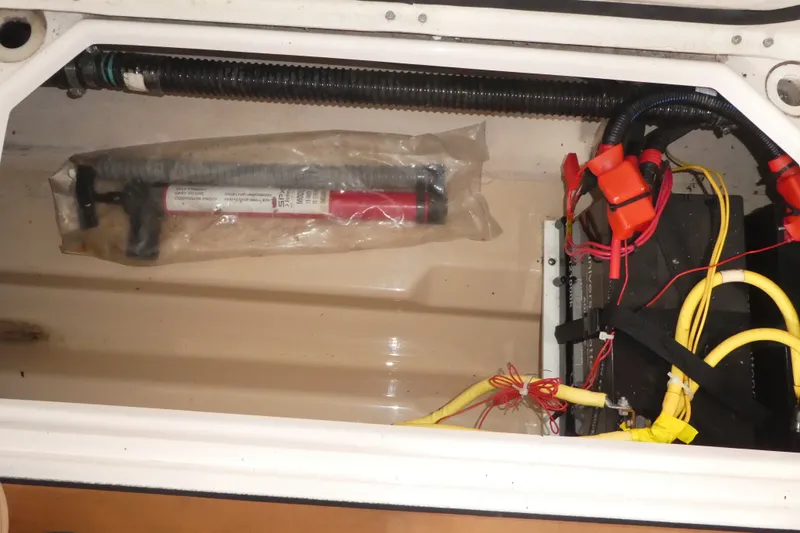 Slide: The Image of 2019 Ranger Tugs R-27 boat compartment with wiring and a sealed manual pump. - 50