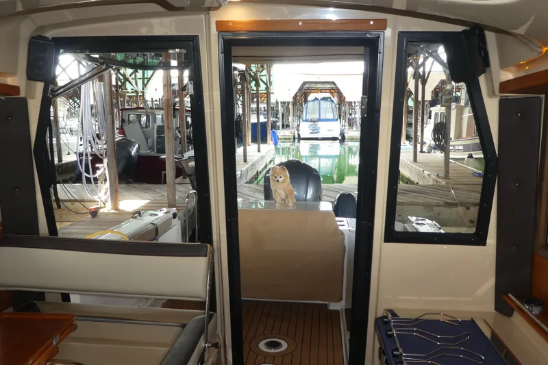Slide: The Image of 2019 Ranger Tugs R-27 interior with dock view and small dog on seat. - 57
