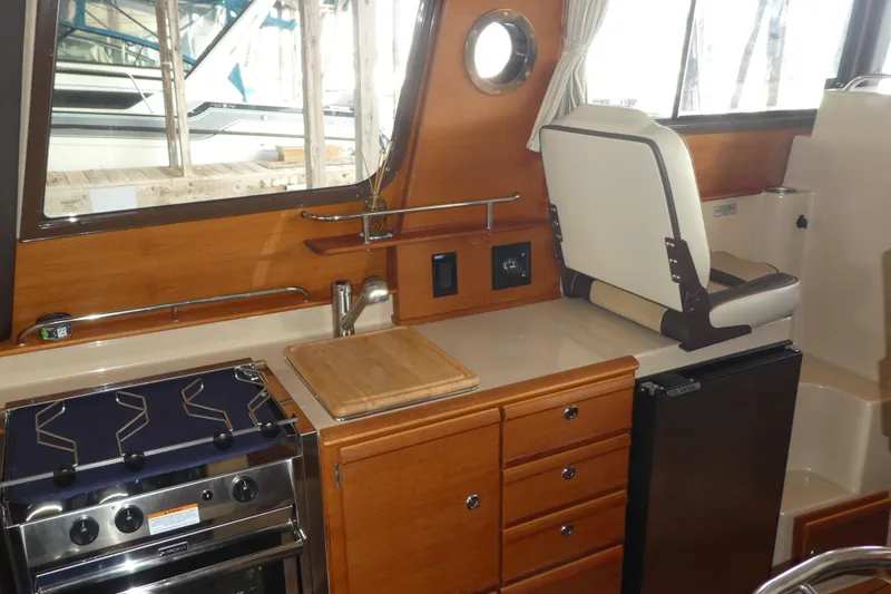 Slide: The Image of 2019 Ranger Tugs R-27 interior kitchen with stove, sink, and seating. - 22