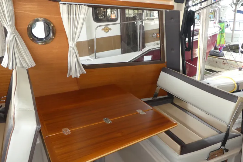 Slide: The Image of Interior of 2019 Ranger Tugs R-27 with wooden table and cushioned seating. - 27