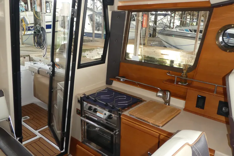 Slide: The Image of 2019 Ranger Tugs R-27 interior with kitchen, stove, and wooden cabinetry. - 31