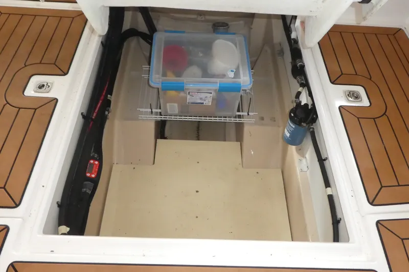 Slide: The Image of 2019 Ranger Tugs R-27 storage compartment with organized plastic container and wooden flooring. - 51
