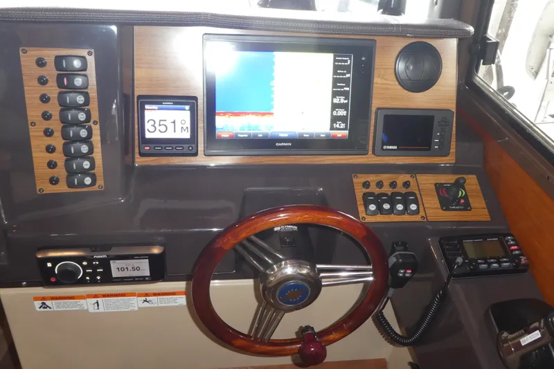Slide: The Image of 2019 Ranger Tugs R-27 helm with Garmin navigation, wooden steering wheel, and control panel. - 29