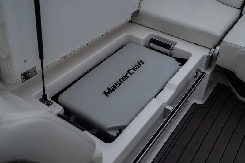 Slide: The Image of 2023 MasterCraft XT24 boat storage compartment with branded cover, showcasing sleek interior design. - 27