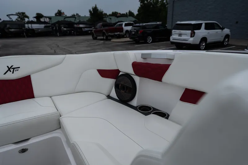 Slide: The Image of 2023 MasterCraft XT24 boat interior with white and red seating, speaker, and cup holders. - 21