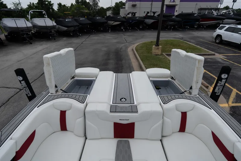 Slide: The Image of 2023 MasterCraft XT24 boat interior with white and red seating, open storage compartments. - 29