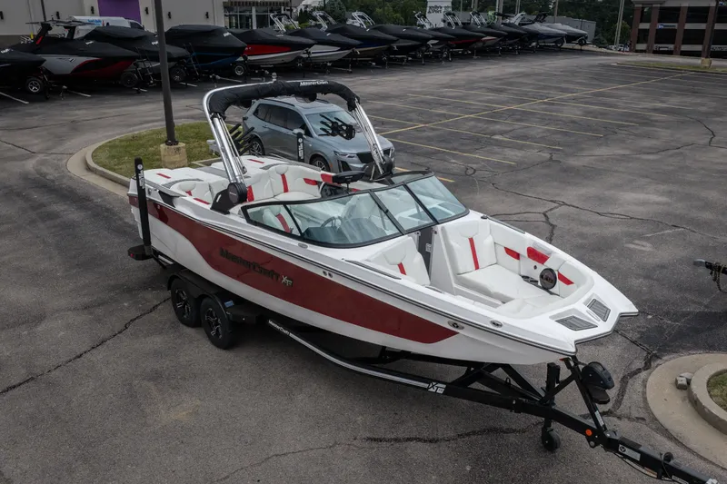 Slide: The Image of 2023 MasterCraft XT24 boat on trailer in parking lot, showcasing sleek design and spacious interior. - 42