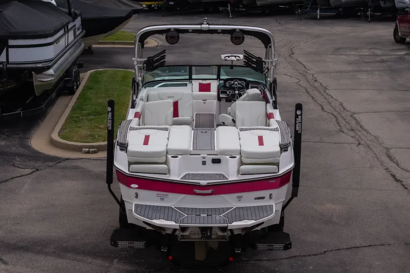 Slide: The Image of 2023 MasterCraft XT24 boat with white and pink seating, parked on pavement. - 48