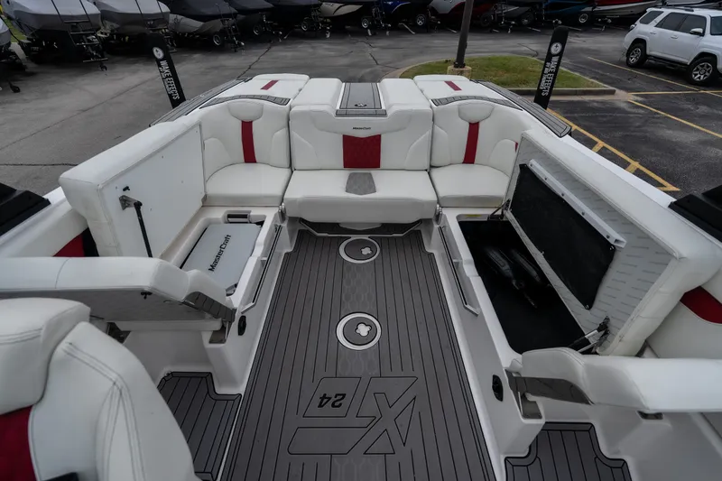 Slide: The Image of 2023 MasterCraft XT24 boat interior with white and red seating, open storage compartments. - 26
