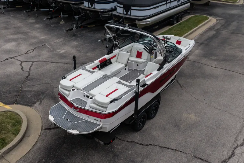 Slide: The Image of 2023 MasterCraft XT24 boat with red and white interior, parked on a trailer. - 47