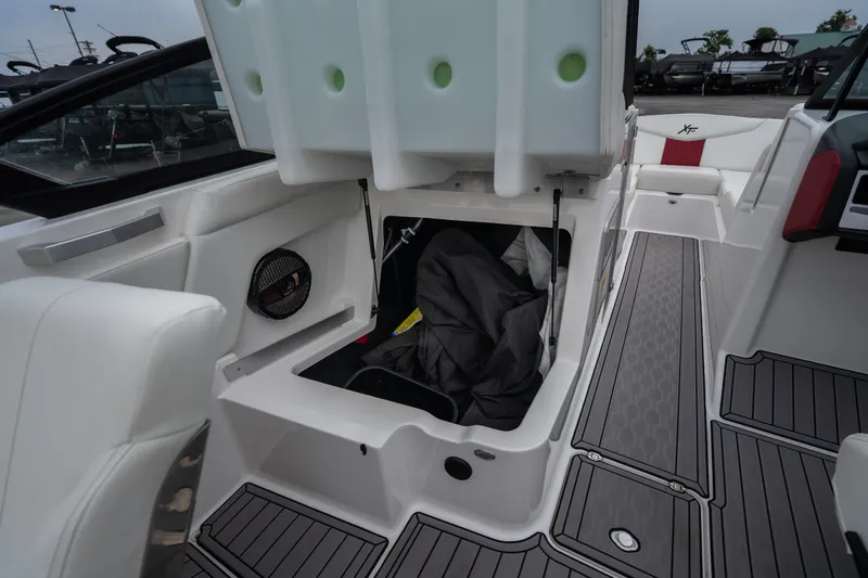 Slide: The Image of 2023 MasterCraft XT24 boat interior storage compartment with open hatch and seating area. - 23