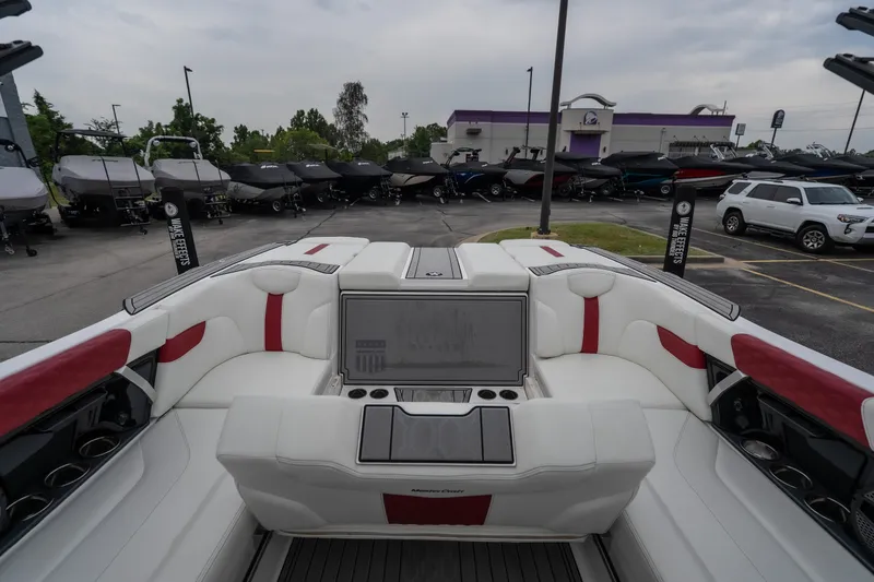 Slide: The Image of 2023 MasterCraft XT24 boat interior with white and red seating, parked at dealership. - 28