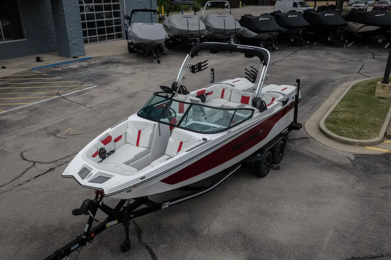 Slide: The Image of 2023 MasterCraft XT24 boat with red and white interior on a trailer in a parking lot. - 41