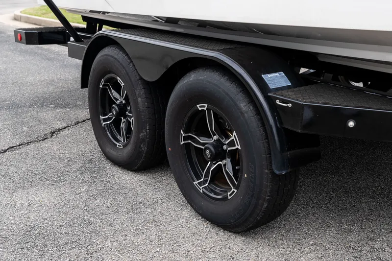 Slide: The Image of Trailer wheels of a 2023 MasterCraft XT24 boat on asphalt pavement. - 45