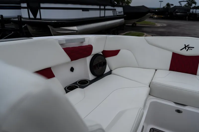 Slide: The Image of 2023 MasterCraft XT24 boat interior with white and red seating, cup holders, and speaker. - 20