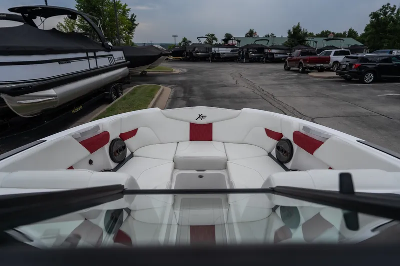 Slide: The Image of 2023 MasterCraft XT24 boat interior with white and red seating, parked in a marina. - 19