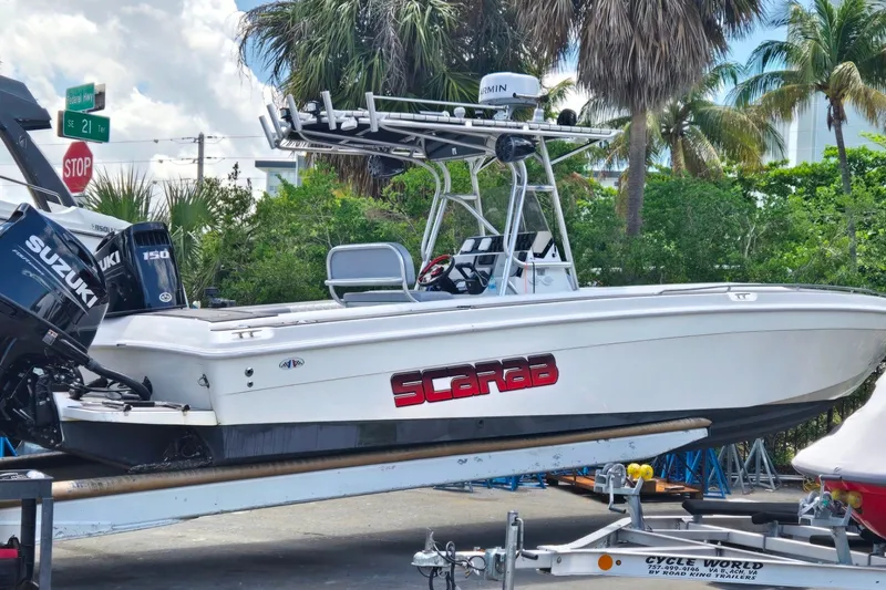 Slide: The Image of 1997 Wellcraft 30 Scarab Sport boat on trailer with Suzuki engines, surrounded by palm trees. - 19