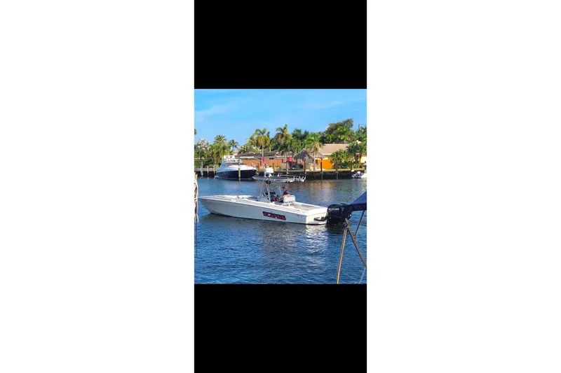 Slide: The Image of 1997 Wellcraft 30 Scarab Sport boat on a sunny waterfront with palm trees. - 24