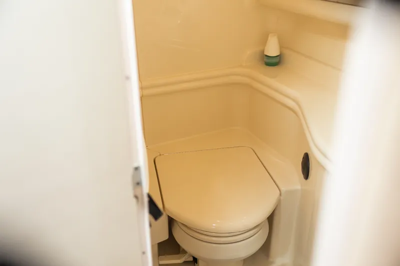 Slide: The Image of 2005 Sea Ray 340 Sundancer boat bathroom with compact toilet and storage shelf. - 21