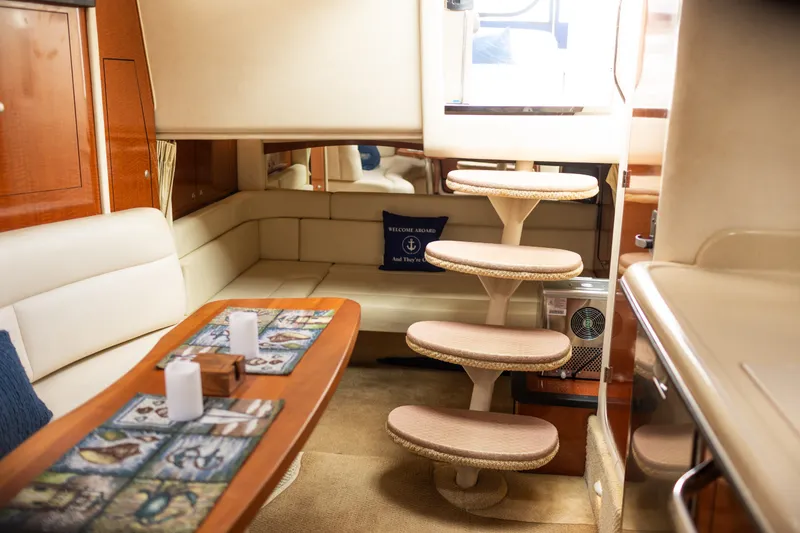 Slide: The Image of Interior of 2005 Sea Ray 340 Sundancer yacht with cozy seating and elegant wooden table. - 16