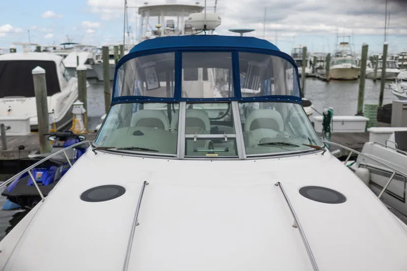Slide: The Image of 2005 Sea Ray 340 Sundancer docked at a marina, showcasing sleek design and blue canopy. - 3